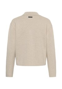 Pull en maille beige à manches longues avec un col, un ourlet droit et une petite étiquette noire rectangulaire en haut du dos portant l'inscription "IW. EDITION".