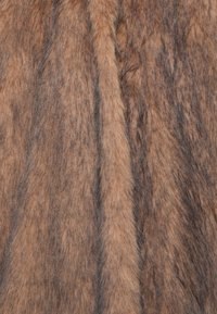 Tessuto in pelliccia sintetica in tonalità di marrone, caratterizzato da una superficie morbida e testurizzata con striature più scure e diverse lunghezze di pelo.