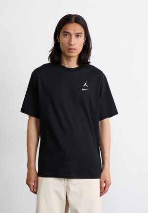 Black cotton T-shirt with short sleeves. Features a white Jordan logo and a white Nike swoosh on the front. Relaxed fit, classic design.