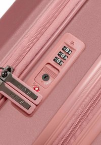 Hartschalenkoffer in zartem Pink mit zwei silbernen Reißverschlüssen. Verfügt über ein Zahlenschloss mit drei Drehrädern und einem TSA-Logo.