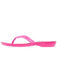 Klart rosa flip-flop sandaler med platt sula och tunna, snurrade remmar, visade från sidan på en vit bakgrund.