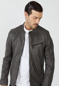 Ciemnoszara skórzana kurtka z prążkowaniem na ramionach, zamykaną na zamek kieszenią na piersi oraz kieszeniami po bokach. Posiada stójkę i dopasowany krój.