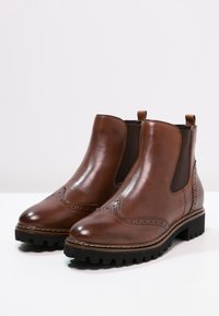 Bottines en cuir marron avec des panneaux latéraux en élasthanne, bout arrondi, détails perforés et semelle en caoutchouc noir durable.