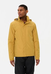 Giacca impermeabile gialla con cappuccio, zip frontale e polsini regolabili. Presenta il logo sul petto e una texture liscia e leggera.