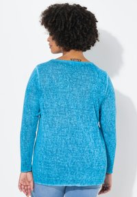 Maglietta a maniche lunghe di un blu brillante, realizzata in un morbido tessuto testurizzato con una vestibilità comoda. Presenta un collo rotondo e un orlo leggermente curvo.