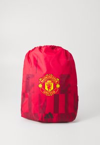 Rød træksæk til sport med mørkerøde geometriske mønstre, Manchester United logo i gul og rød, samt sort Adidas logo nederst.