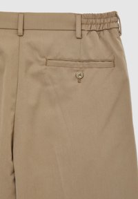 Pantaloni beige con vita elastica, dal tessuto liscio, dotati di una tasca posteriore chiusa da un bottone e passanti per cintura cuciti.