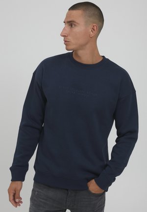 Marineblauwe sweatshirt met een ronde hals, ribgebreide manchetten en een textuur logo aan de voorkant. De stof lijkt zacht met een gladde afwerking.