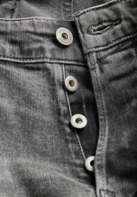 Nahaufnahme von offen stehenden grauen Jeans mit Metallknöpfen, Knopfloch und genähten Nähten.