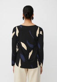Zwart langemouwshirt met abstracte bladerenpatronen in roomwit en marineblauw, zachte stof, ronde halslijn en een relaxte pasvorm.