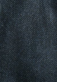 Tissu en laine présentant un motif en chevron bleu foncé avec une surface texturée et des variations subtiles de teintes, offrant profondeur et intérêt.