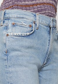 Ljusblå denimjeans med hög midja, med en liten framficka, kopparnitar och subtil detaljerad söm i slitage.