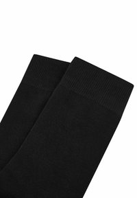 Schwarze Socken aus glattem Stoff mit einem gerippten Bund. Das Design verfügt über eine nahtlose Oberseite und eine einheitliche dunkle Farbe im gesamten Verlauf.