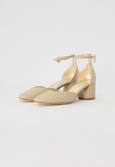 Goldene Glitzer-Ankle-Strap-Absätze mit spitzem Zehenbereich und Blockabsatz. Der Riemen hat eine kreisförmige Schnallendekoration. Das Innere ist glatt und glänzend.