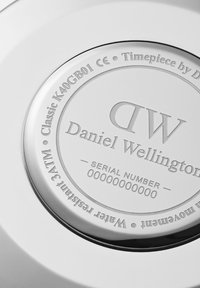 Stainless steel watch case back engraved with "Daniel Wellington," "DW," and water resistance details. Smooth, polished surface.
