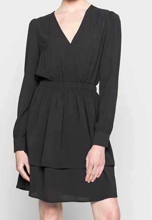 Sort kjole med lange ærmer, V-hals, indsnøret talje og lagdelt skørt. Fremstillet af letvægtsstof med glat tekstur.