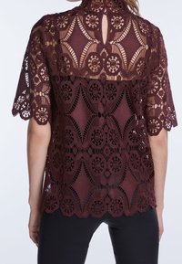 Burgundy blonde med korte ærmer, indviklede blomstermotiver og en høj halsudskæring med en nøglehuldetalje bagpå.