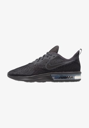 Zapatilla de correr Nike Air Max negra con parte superior de malla, media suela de espuma, cámara de aire visible en el talón y el logo de Nike swoosh en el lateral.