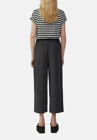 Top à manches courtes noir et blanc à rayures avec un ourlet arrondi, associé à un pantalon large cropped noir et des sandales à plateforme noires.