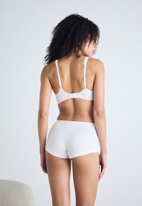 White cotton bra and shorts set, featuring adjustable straps, a smooth texture, and a simple design with minimal stitching details.