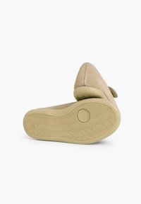 Zapato de ante beige con una suela de goma flexible, punta afilada y un diseño simple. Presenta una superficie texturizada sin patrones o acentos visibles.