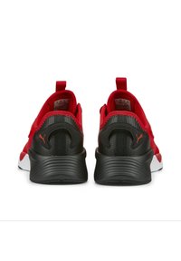Chaussures de sport rouges avec des accents noirs, présentant une tige en mesh, un col rembourré, un talon plat, et un logo bien visible à l'arrière.