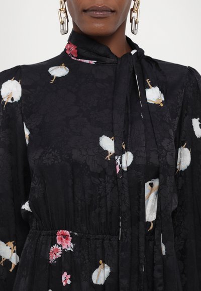 Zwart gestippelde jurk met bloemen- en zwanenmotieven, voorzien van een hoge kraag, lange mouwen en een geplooide taille voor een losse pasvorm.