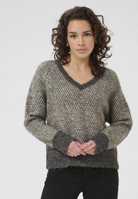 Gebreide trui in grijs en beige met een V-hals, chunky textuur en geribde manchetten. Heeft een losse pasvorm en een golvende zoom.