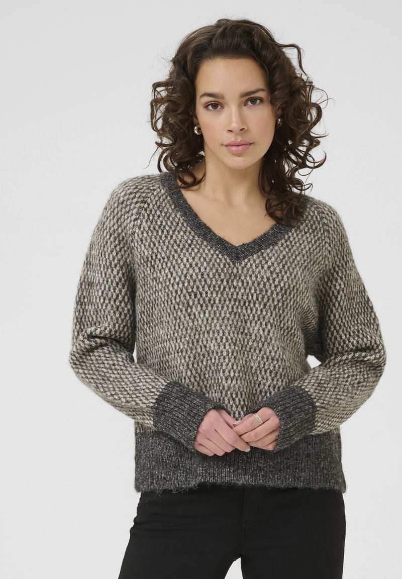 Gebreide trui in grijs en beige met een V-hals, chunky textuur en geribde manchetten. Heeft een losse pasvorm en een golvende zoom.