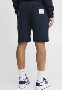 Mørkeblå, bomullsblande shorts med avslappet passform, med en baklomme og et merke. Linningen er avsluttet med en enkel søm.