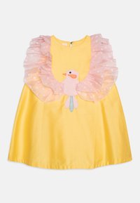Robe jaune avec un col à volants à pois roses et un motif d'oiseau appliqué sur le devant. Tissu lisse avec une forme ample et évasée.