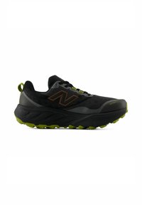 Chaussure de sport New Balance noire et verte avec semelle épaisse, tige en mesh et logo "N" sur le côté, conçue pour la course en sentier ou la randonnée.