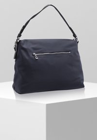 Granatowa torebka nylonowa z przednią kieszenią na zamek błyskawiczny w kolorze srebrnym, gładką fakturą oraz krótkim, odczepianym czarnym paskiem.