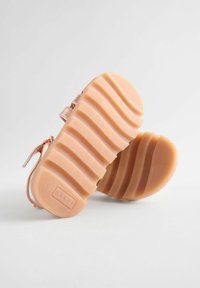 Roze gouden sandalen met platte rubberen zolen, geperforeerde patronen, verstelbare banden en een merkafdruk op de zool.