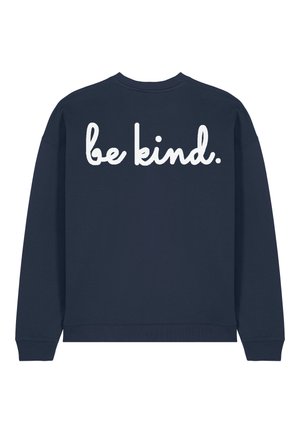 Marineblauwe sweatshirt met geribbelde ronde hals en manchetten. Eenvoudige achterkant met grote witte tekst die "wees aardig" van schouder tot schouder leest.
