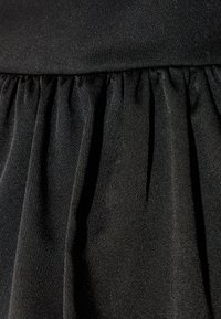 Tissu noir avec un subtil éclat, présentant une texture froncée et des plis fluides. Surface lisse avec des accents scintillants tout au long.