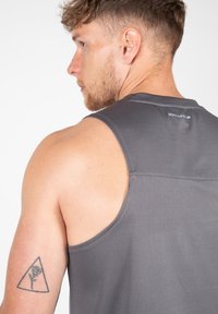 Halli särg, millel on lühikesed varrukad ja mis on valmistatud hingavast kangast, ümar kaelus ja logo detail taga. Õrn tekstuuriline muster.