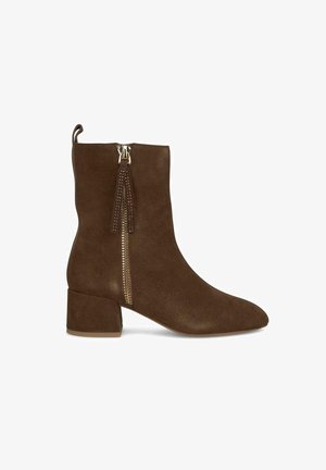 Botte chelsea en daim marron avec un bout pointu, un talon carré et une fermeture éclair latérale, ornées d'accents métalliques décoratifs et d'un faux gland.