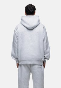 Felpa grigia chiara con vestibilità rilassata, cappuccio oversize e polsini e orlo a costine. Realizzata in morbido tessuto testurizzato.