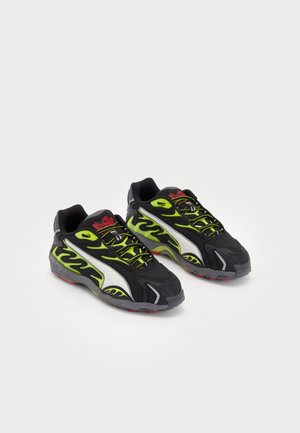 Sapatilhas atléticas pretas com detalhes em chamas verde neon, sobreposições prateadas e uma sola texturizada com detalhes em vermelho e cinza. Design com atacadores.
