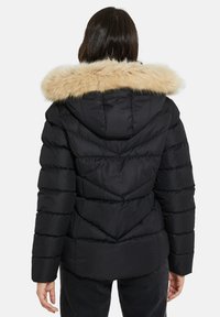 Zwarte gewatteerde jas met een nep-leren capuchon, verticale gestikte design en een getailleerde silhouet. Zachte textuur en een afneembare capuchon accentueren de warmte.