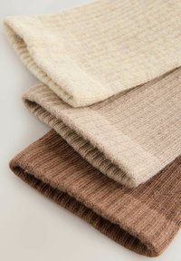 Drie paar geribde sokken in crème, licht taupe en donkerbruin. Elk paar heeft een omgeslagen boord en een zachte textuur.