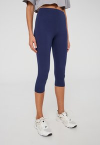 Leggings cropped blu navy realizzati in tessuto elastico, con un alto punto vita e un design liscio e aderente.