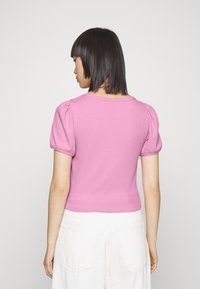 Top ajustado canelado em rosa com mangas curtas bufantes e decote redondo, concebido com um acabamento texturizado.