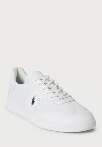 White sneaker with a smooth leather finish, lace-up design, rounded toe, and navy Polo logo on the side. Rubber sole and padded collar.