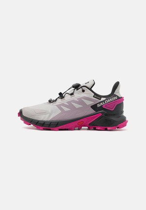 Lysegrå og pink Salomon trail løbesko med sort sål, hurtig snøresystem og Gore-Tex label på siden.
