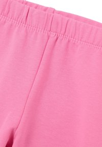 Leggings rosa claro con una suave tela de mezcla de algodón, cinturilla elástica y costuras simples a lo largo de los bordes.