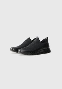 Black slip-on shoes with a textured knit upper and smooth rubber sole. Features pull tabs and a flexible, cushioned design.