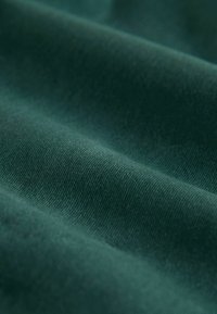 Tissu vert profond avec une texture lisse, présentant un léger éclat et des lignes diagonales, mettant en valeur une apparence légère et douce.