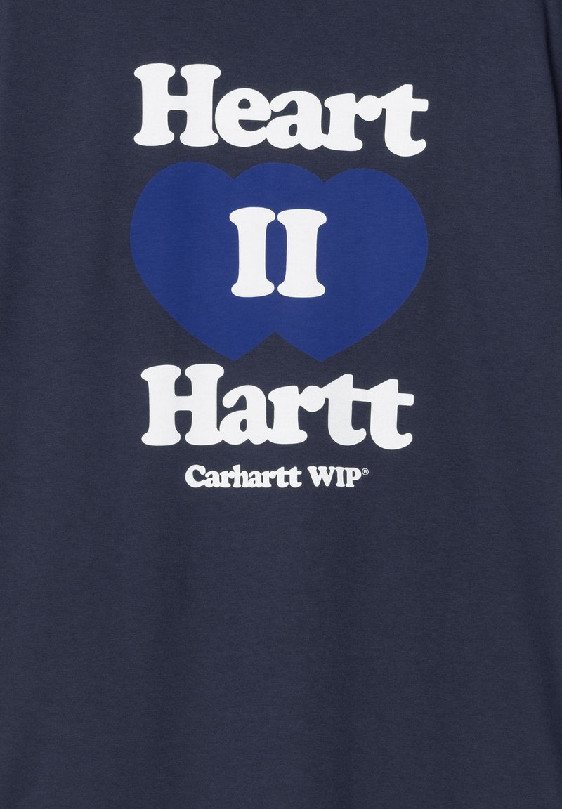 Camiseta de algodón azul marino con un atrevido texto blanco que dice "Heart II Hartt" junto con un gráfico de corazón azul y el logo de "Carhartt WIP" en la parte inferior.
